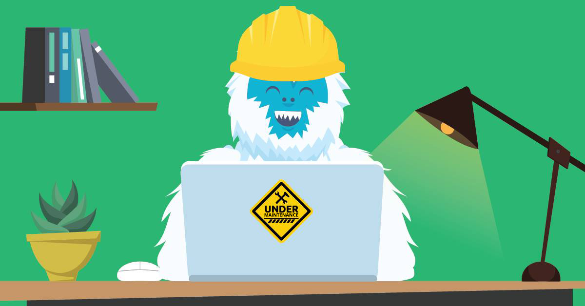 a yeti sitting and working on a laptop with a yellow hat